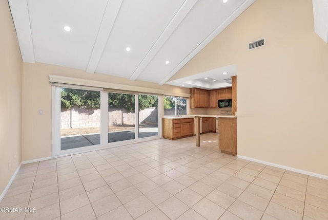 kitchen featuring beam ceiling, sink, light tile patterned floors, and high vaulted ceiling