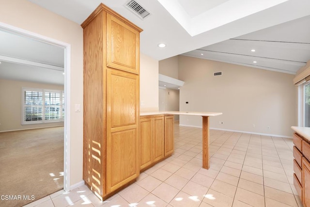 kitchen with lofted ceiling, light tile patterned floors, and light brown cabinetry