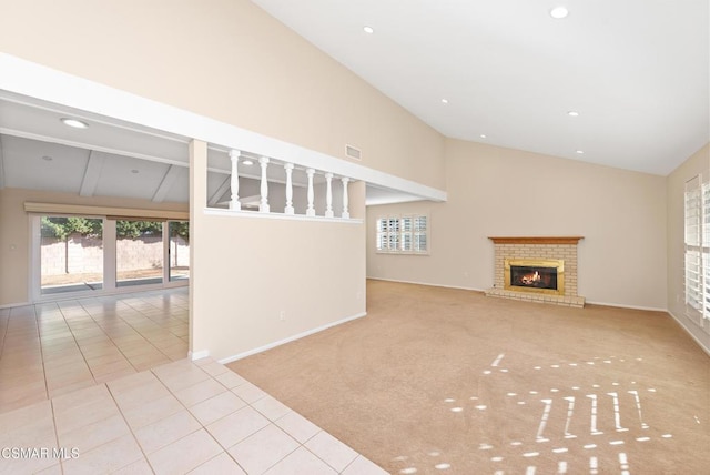 unfurnished living room featuring a brick fireplace, light carpet, and high vaulted ceiling