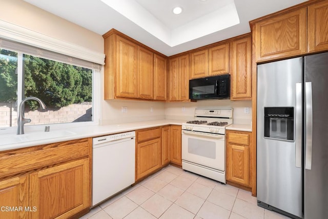 kitchen with white appliances, a raised ceiling, sink, and light tile patterned floors