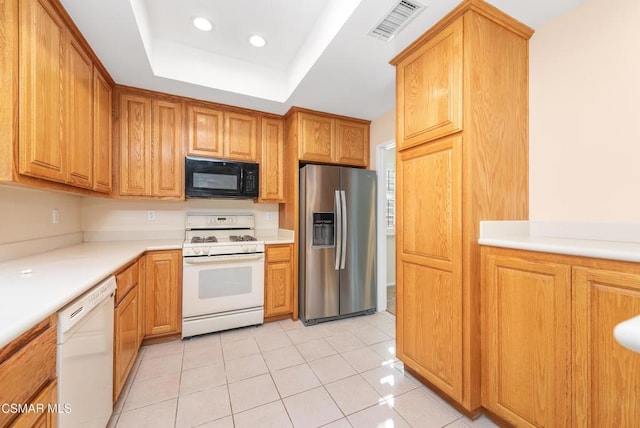 kitchen with light tile patterned floors, white appliances, and a raised ceiling