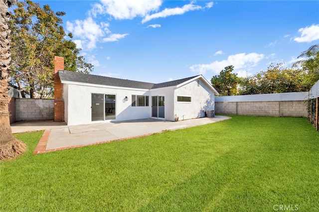 rear view of house featuring a fenced backyard, a lawn, stucco siding, a chimney, and a patio area