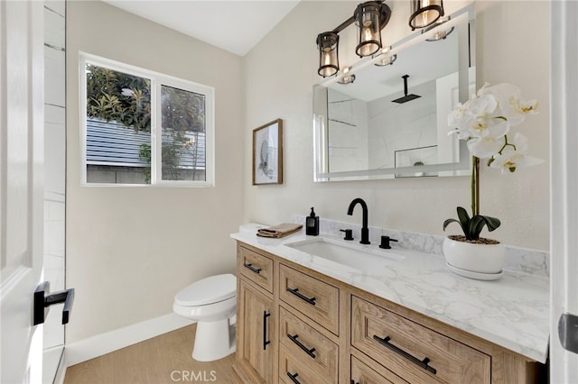 bathroom featuring toilet, wood finished floors, vanity, baseboards, and walk in shower