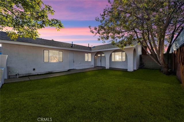 view of front of home with fence private yard, stucco siding, and a yard