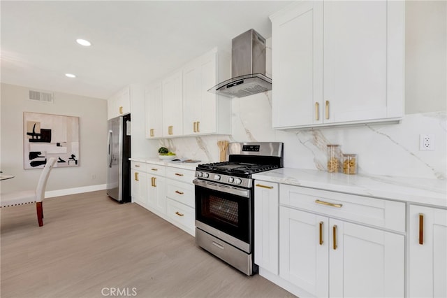 kitchen with visible vents, light wood-style flooring, appliances with stainless steel finishes, wall chimney range hood, and white cabinetry