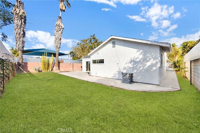 back of house featuring a lawn, a patio, a fenced backyard, central air condition unit, and stucco siding