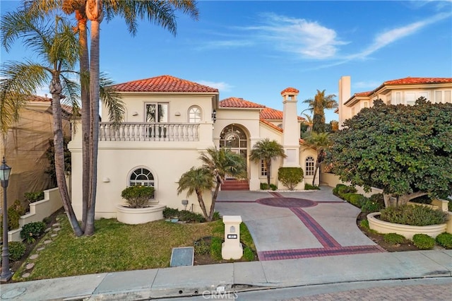 mediterranean / spanish-style house featuring a balcony and a front lawn