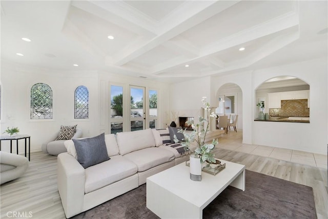 living room with coffered ceiling, ornamental molding, beamed ceiling, and light wood-type flooring