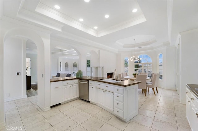 kitchen featuring a tray ceiling, white cabinetry, sink, ornamental molding, and kitchen peninsula