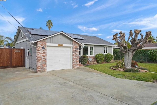 ranch-style home with a garage, a front yard, and solar panels