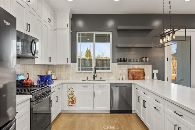 kitchen with stainless steel appliances, hanging light fixtures, sink, and white cabinets