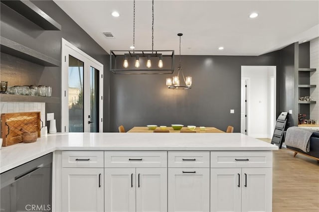 kitchen featuring white cabinetry, hanging light fixtures, light hardwood / wood-style floors, and an inviting chandelier