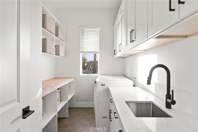 washroom featuring sink, light tile patterned floors, washer and clothes dryer, and cabinets