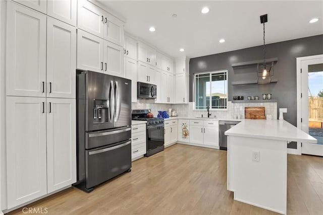 kitchen with appliances with stainless steel finishes, white cabinetry, sink, hanging light fixtures, and a healthy amount of sunlight