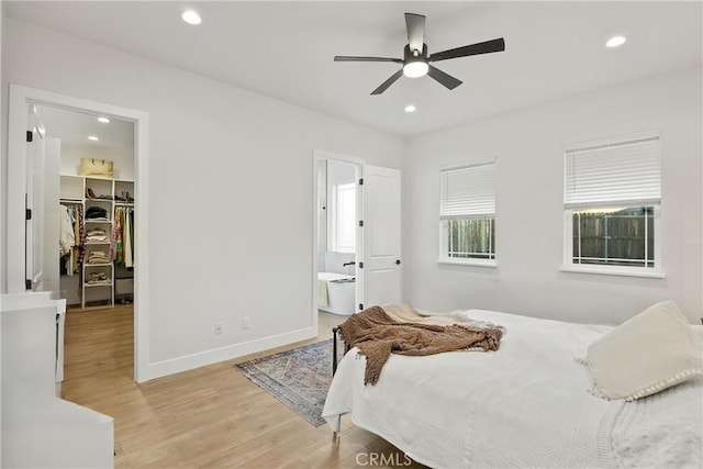 bedroom with ceiling fan, ensuite bathroom, light hardwood / wood-style floors, a walk in closet, and a closet