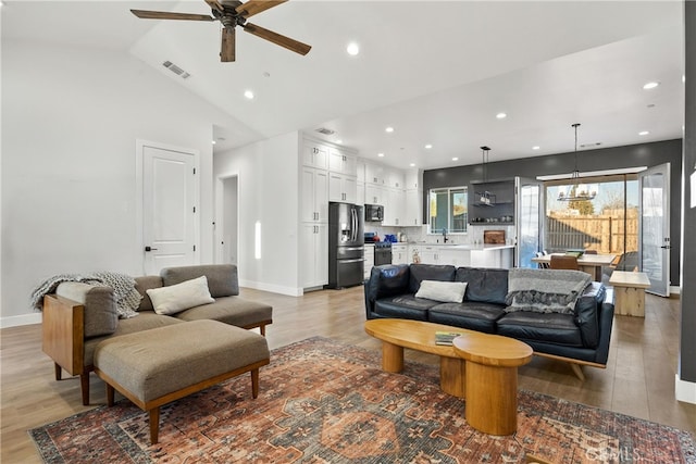 living room with lofted ceiling, sink, and light hardwood / wood-style floors