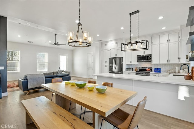 dining room with sink, light hardwood / wood-style floors, and ceiling fan