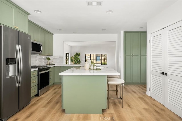 kitchen featuring stainless steel appliances, green cabinetry, and a kitchen bar