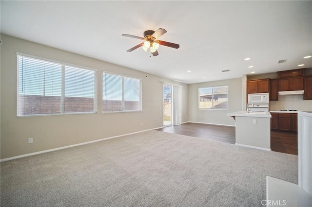 kitchen with ceiling fan, white appliances, carpet, and a kitchen island