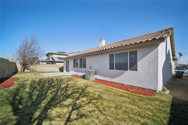 back of property with a lawn, central air condition unit, and a patio area