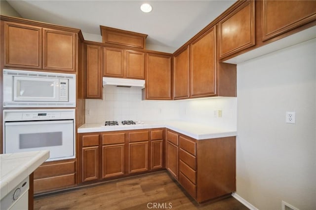 kitchen with dark hardwood / wood-style floors, tile countertops, white appliances, and decorative backsplash