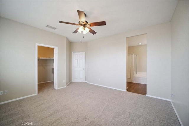 unfurnished bedroom with ceiling fan, connected bathroom, carpet floors, a spacious closet, and a closet