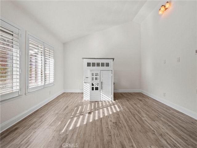 unfurnished living room featuring hardwood / wood-style floors and vaulted ceiling