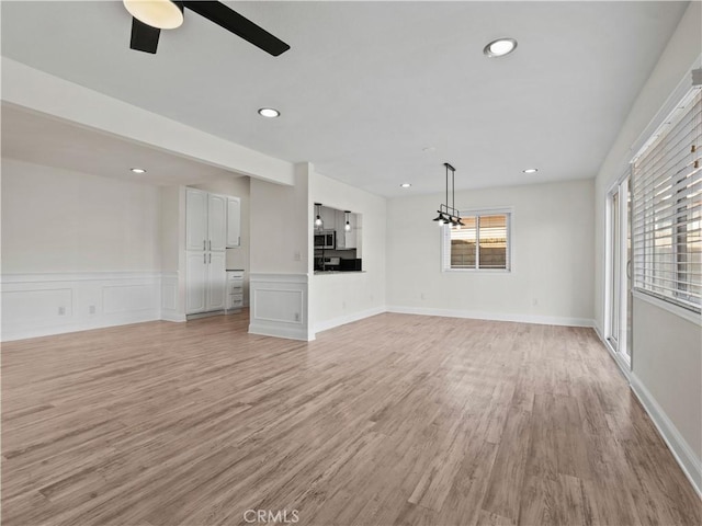 unfurnished living room featuring ceiling fan and light hardwood / wood-style flooring