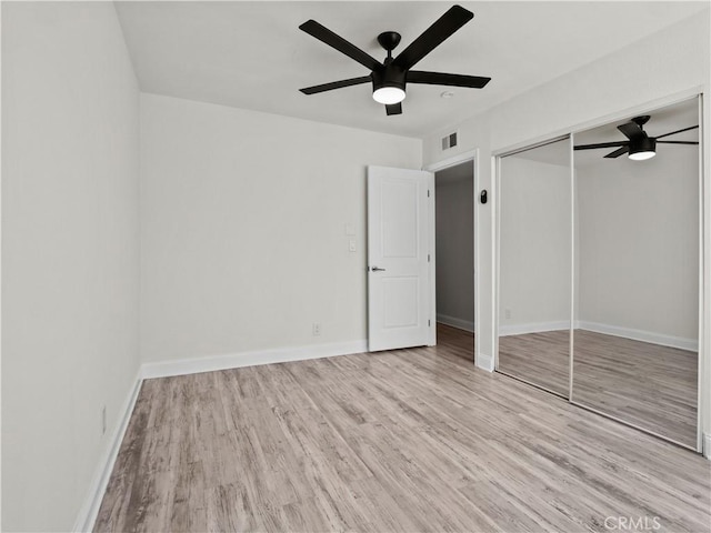 unfurnished bedroom featuring ceiling fan, a closet, and light wood-type flooring