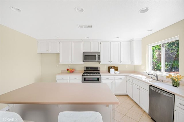 kitchen featuring light tile patterned flooring, a breakfast bar, sink, white cabinets, and stainless steel appliances