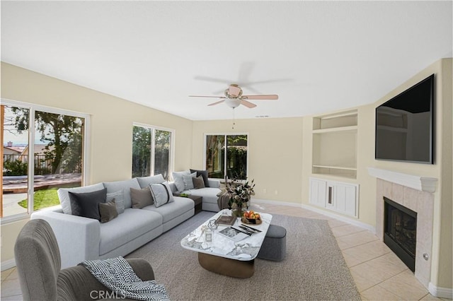 living room featuring light tile patterned flooring, ceiling fan, built in features, and a fireplace