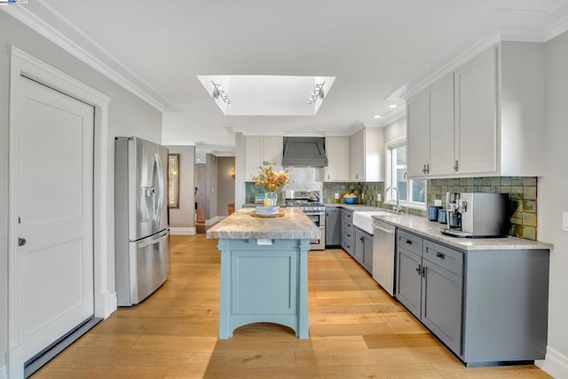 kitchen featuring premium range hood, a skylight, sink, a center island, and stainless steel appliances