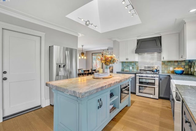 kitchen featuring custom exhaust hood, a kitchen island, white cabinets, and stainless steel appliances