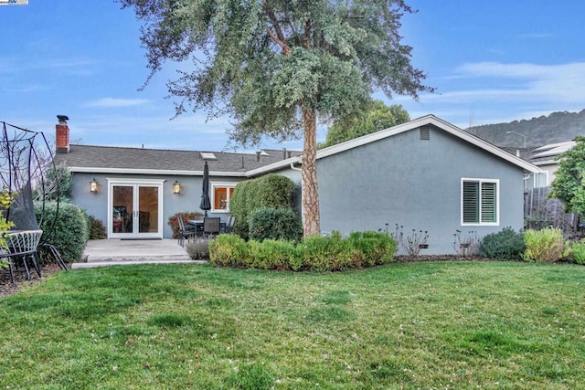 rear view of house featuring a yard, a patio, and french doors