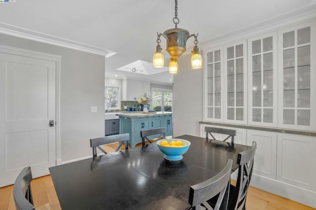 dining space with crown molding and light hardwood / wood-style floors