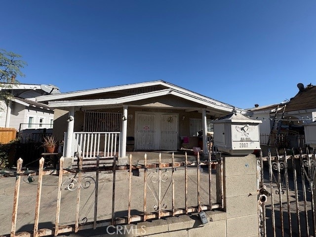 bungalow-style house with a porch, a fenced front yard, and a gate