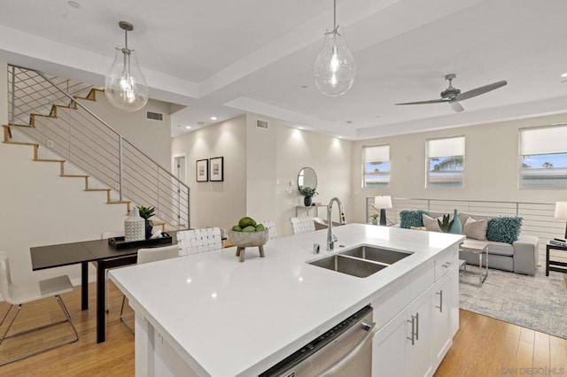 kitchen featuring hanging light fixtures, an island with sink, dishwasher, and sink