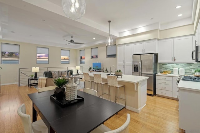 dining space featuring ceiling fan, sink, and light wood-type flooring