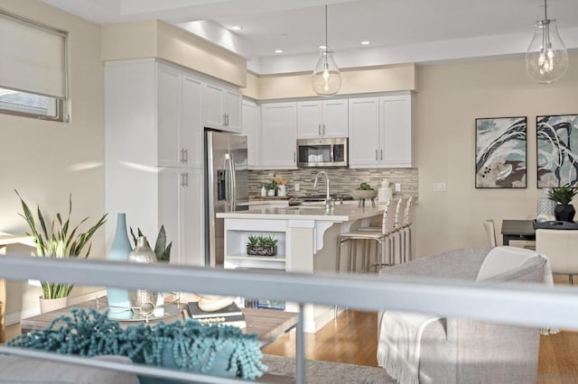 kitchen featuring stainless steel appliances, hanging light fixtures, and white cabinets