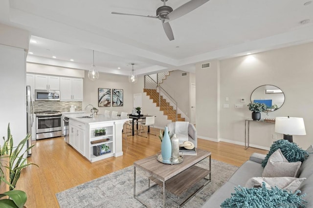 living room featuring sink, ceiling fan, and light wood-type flooring