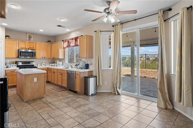 kitchen with a kitchen island, appliances with stainless steel finishes, sink, ceiling fan, and light brown cabinets