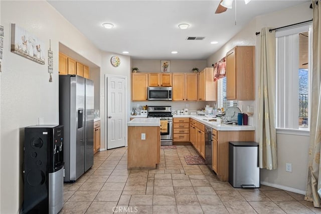 kitchen featuring appliances with stainless steel finishes, a center island, sink, and light brown cabinetry