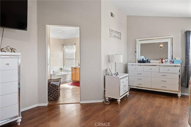 bedroom with ensuite bathroom and dark hardwood / wood-style floors