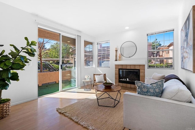 living room with a tile fireplace and light hardwood / wood-style flooring