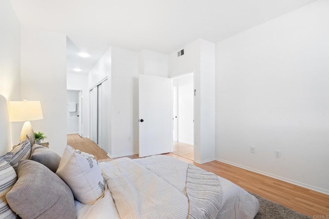 bedroom featuring a closet, visible vents, light wood-style flooring, and baseboards