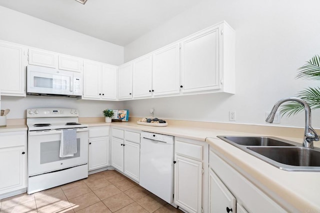 kitchen with white appliances, light tile patterned flooring, a sink, and white cabinetry