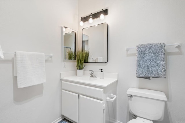 bathroom featuring toilet, baseboards, and vanity