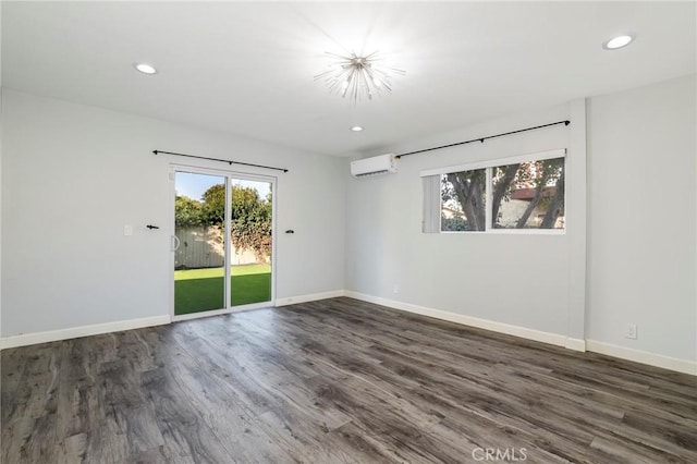 spare room featuring dark hardwood / wood-style flooring, a wealth of natural light, and an AC wall unit