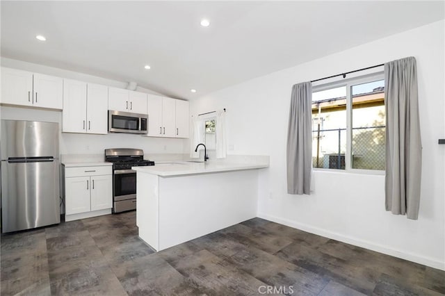 kitchen featuring stainless steel appliances, vaulted ceiling, white cabinets, and kitchen peninsula