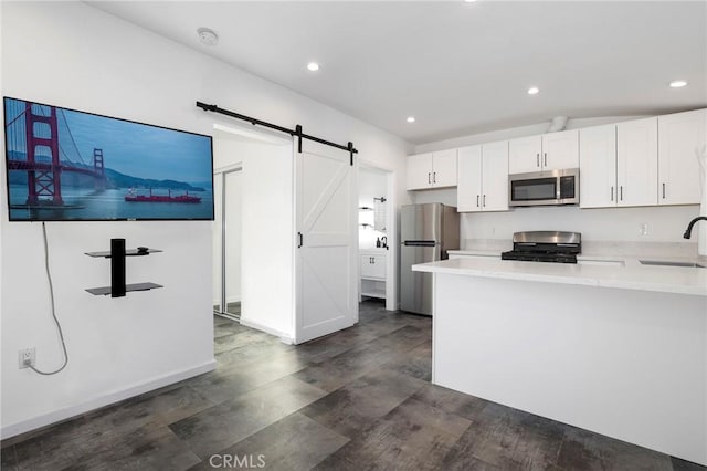 kitchen featuring sink, a barn door, white cabinets, and appliances with stainless steel finishes